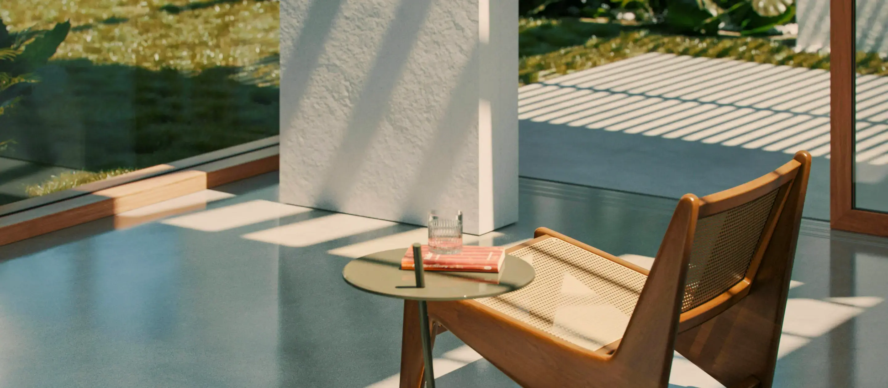 A sunlit modern living room with a wooden chair, round table, book, and glass of water. Shadow patterns create a peaceful and serene atmosphere.
