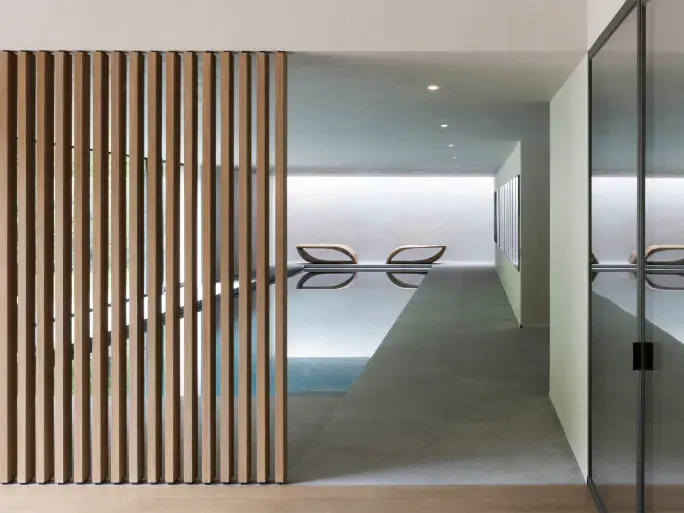Luxury pool view with sunlight streaming through wooden slats in the foreground.